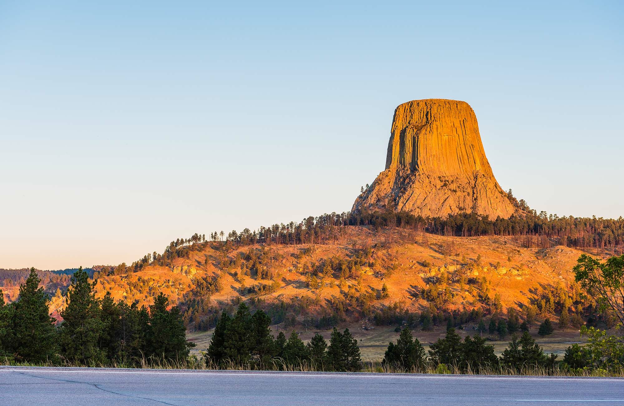 Devils Tower at sunset, a top thing to do in Wyoming, stands tall with golden light highlighting its unique structure.