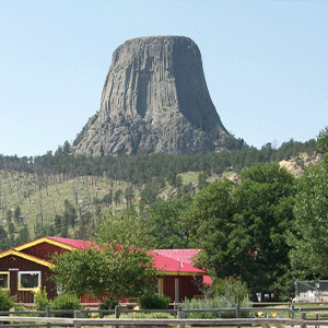 Cabins and trees at the Devils Tower Black Hills KOA and Devils Tower National Monument in the background.