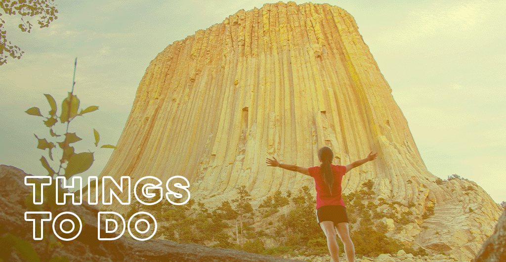 The words, "Things to Do" layered over an image of a person standing with outstretched arms in front of Devils Tower National Monument.