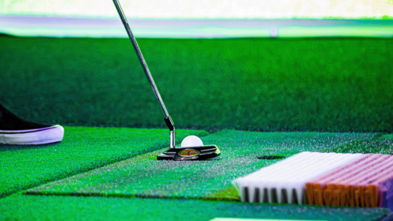 Close-up of a golf club hitting a ball at a golf simulator.