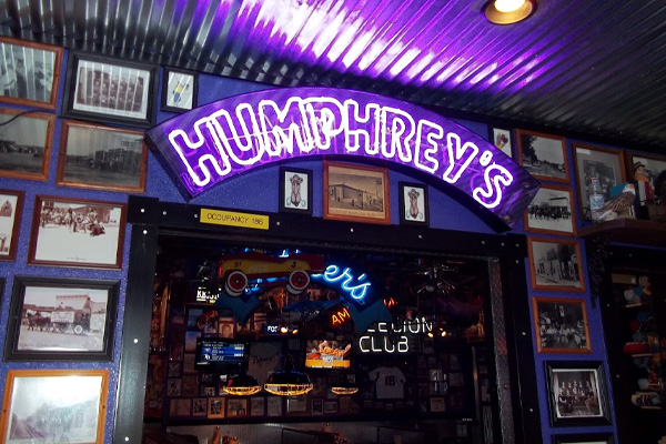 A purple neon light-up sign of Humphrey’s reflects into the silver ceiling at Humphrey’s Bar & Grill, a bar in Gillette, Wyoming.