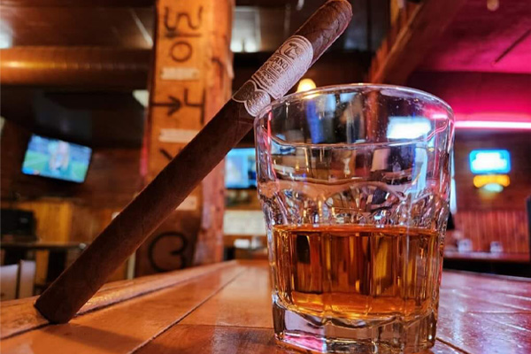 A close-up of a cigar balanced on a glass of liquor at Montgomery Bar.