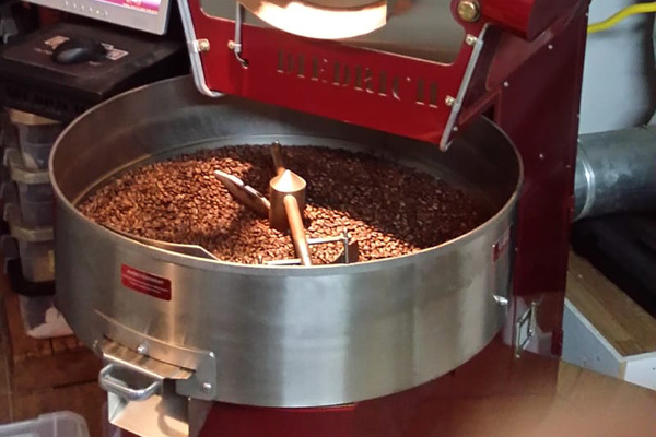A roaster at Wyoming coffee shop, Powder River Espresso, preparing a new batch of coffee beans in the silver and red machine.
