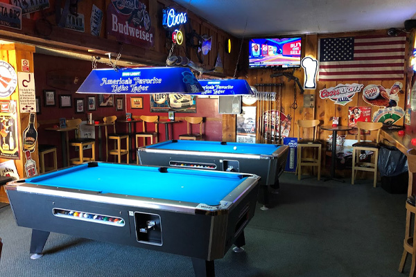 Pool tables in a room at The Office Saloon, a bar in Gillette, Wyoming, where signs for Coors and Budweiser hang up next to an American flag.