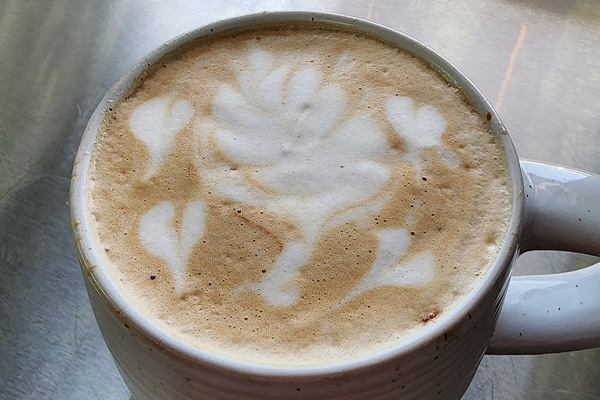 Wyoming coffee shop, Wildheart Coffee Company, serves a fresh mug of java, frothed with latte art, hearts circling a leaf in the middle.
