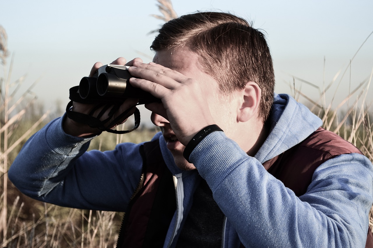 A man uses binoculars to spot wildlife.