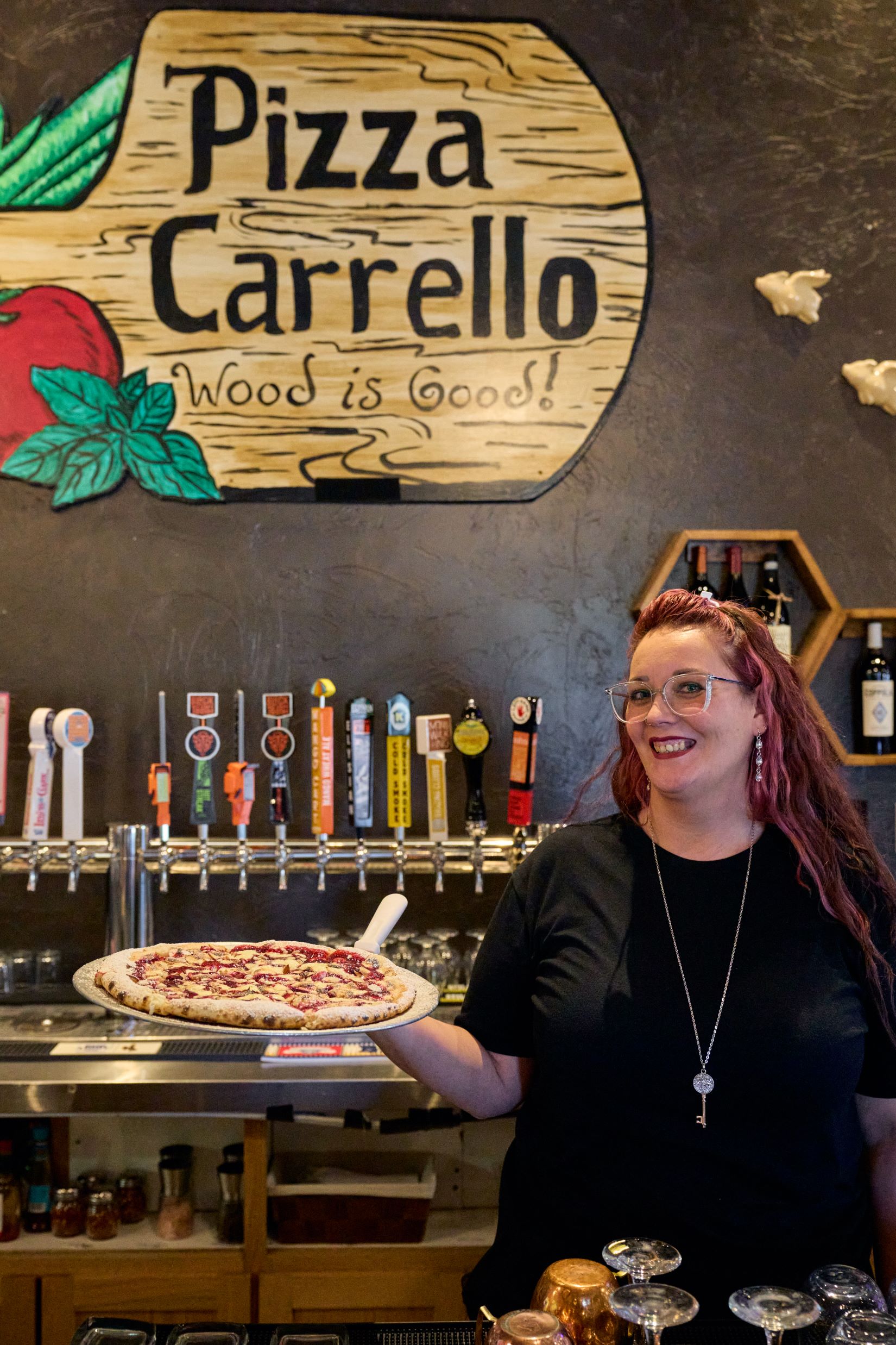 A friendly staff member at Pizza Carrello in Gillette, Wyoming, serving up wood-fired pizza, one of the best places to eat in the area.