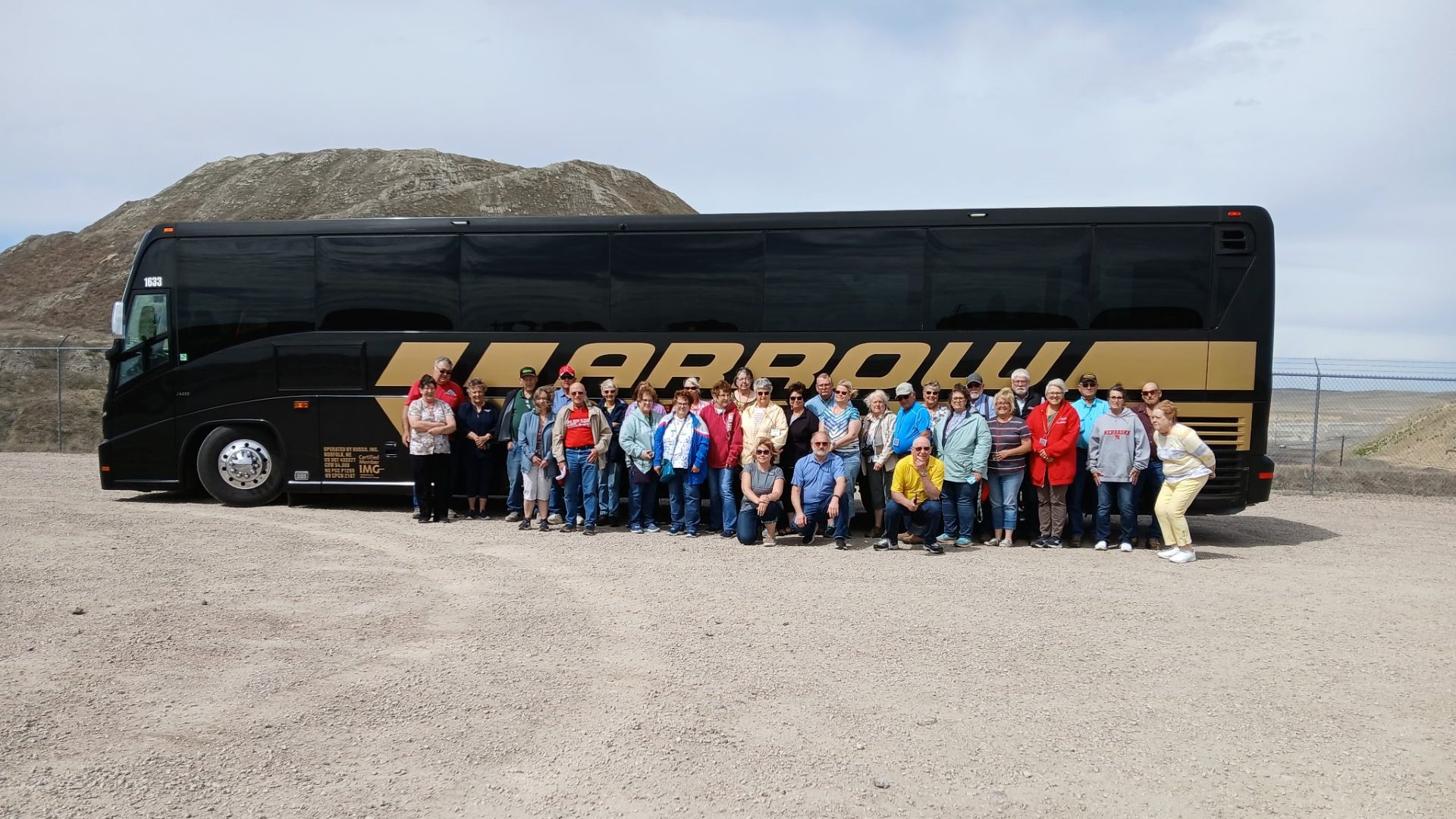 Bus tour group posing in front of Arrow motorcoach at Eagle Butte Mine overlook in Gillette, Wyoming