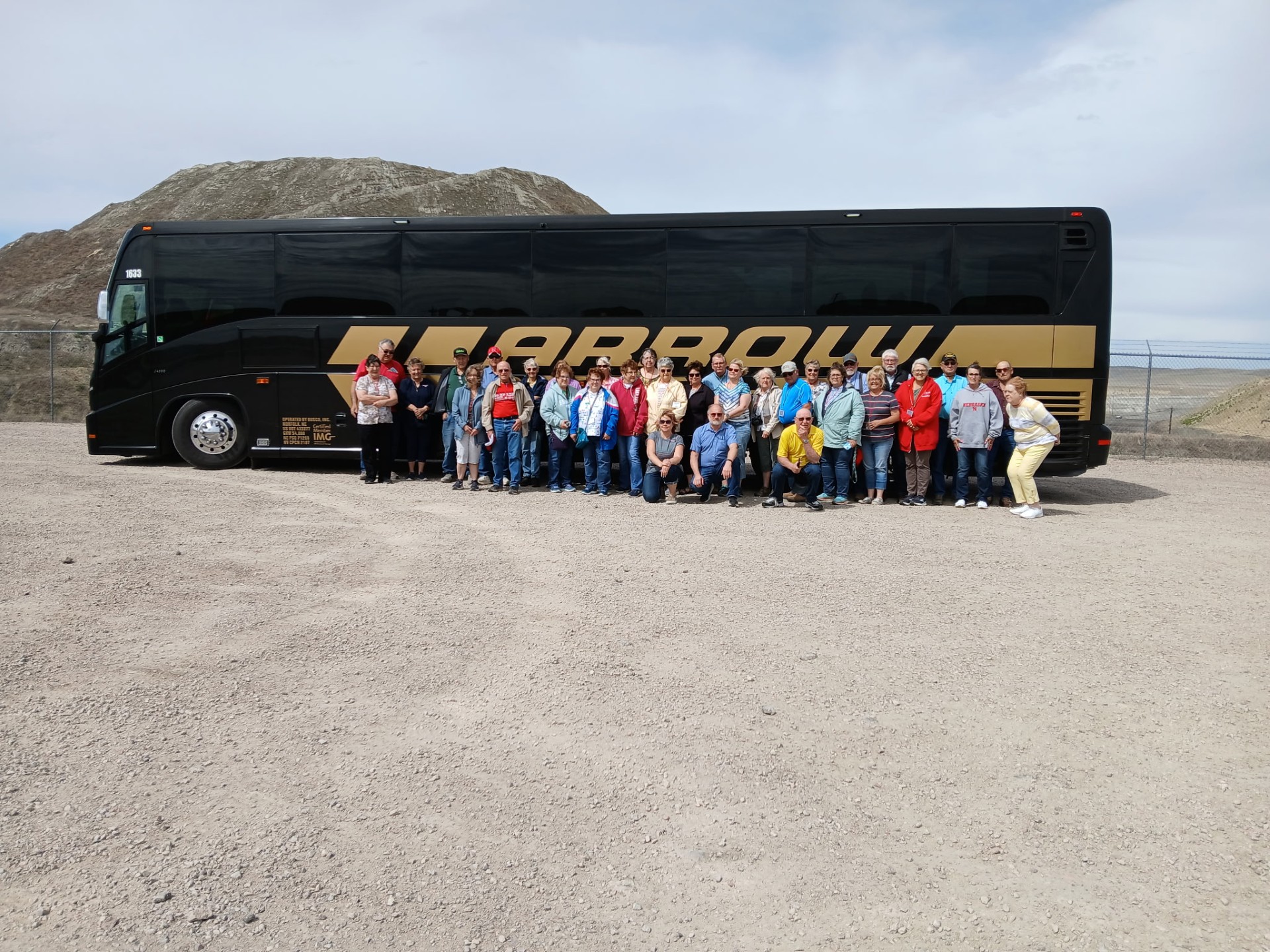 Bus tour group posing in front of Arrow motorcoach at Eagle Butte Mine overlook in Gillette, Wyoming